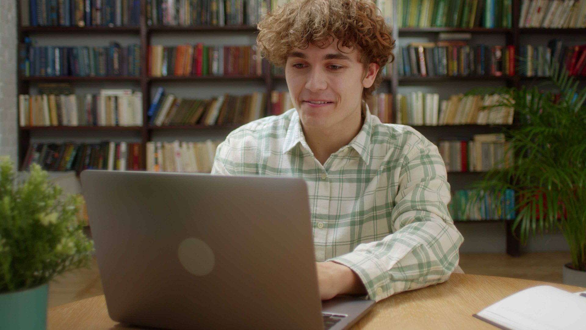 A student working through coursework on a laptop at a library table